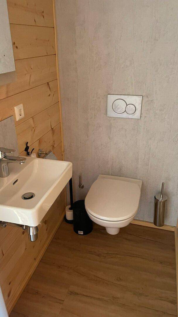 Funktionale Gästetoilette mit modernem Waschbecken, wandhängendem WC und Holzwandverkleidung.