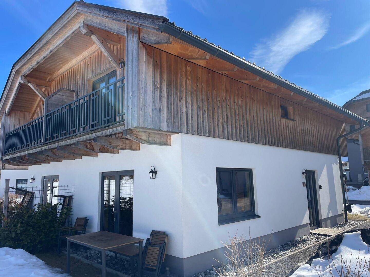 Attraktives Chalet-Gebäude mit Balkon und einer Terrasse im Erdgeschoss, ideal für entspannte Stunden im Freien.
