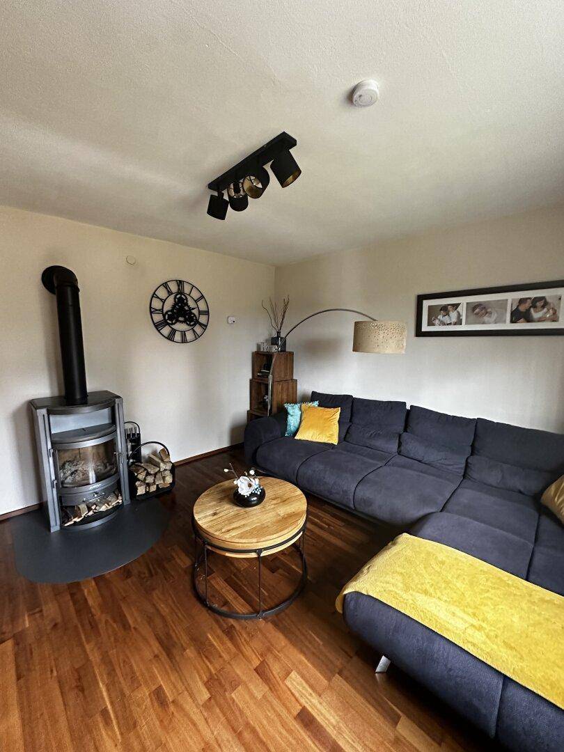 Gemütliches Wohnzimmer mit Kaminofen, Holzboden und bequemer Sitzecke.