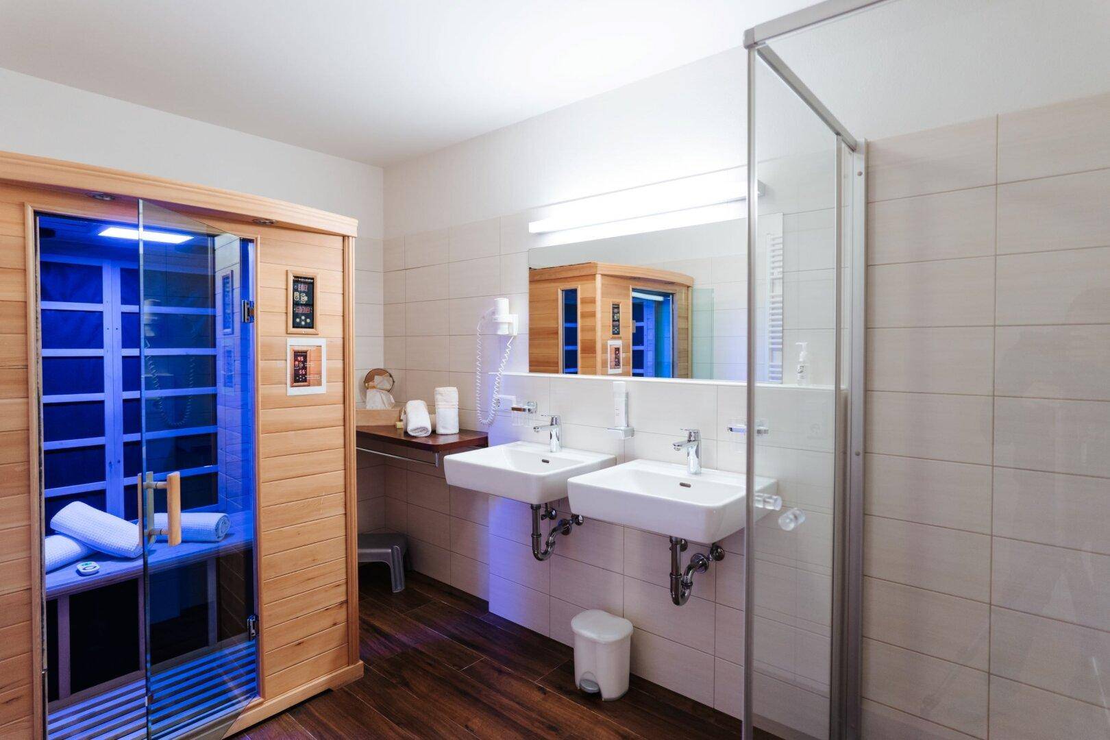 Modernes Badezimmer mit Doppelwaschbecken, Duschkabine und einer integrierten Infrarotsauna.