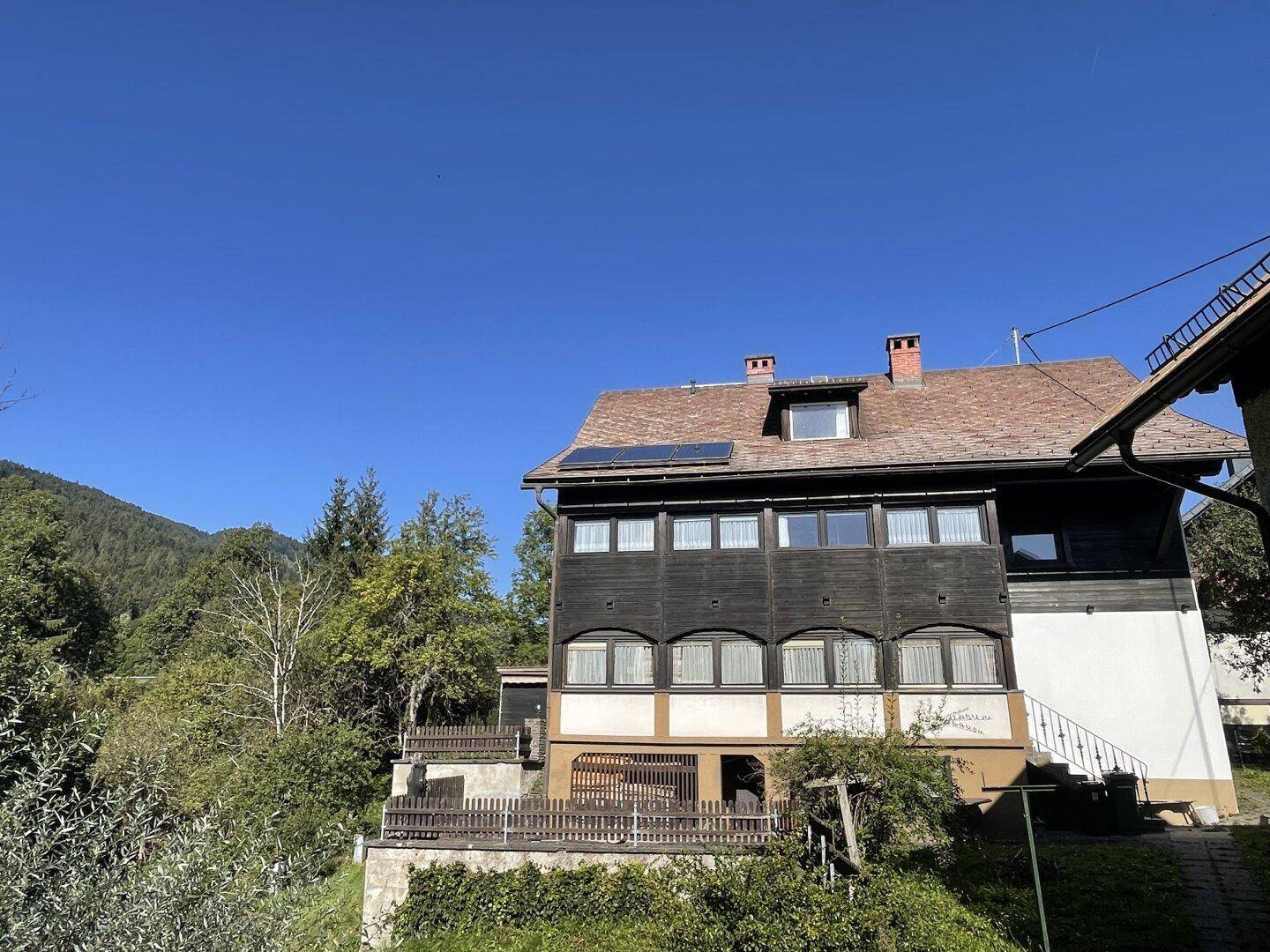 Traditionelles Haus mit dunkler Holzfassade, weißen Akzenten und einem kleinen Balkon.