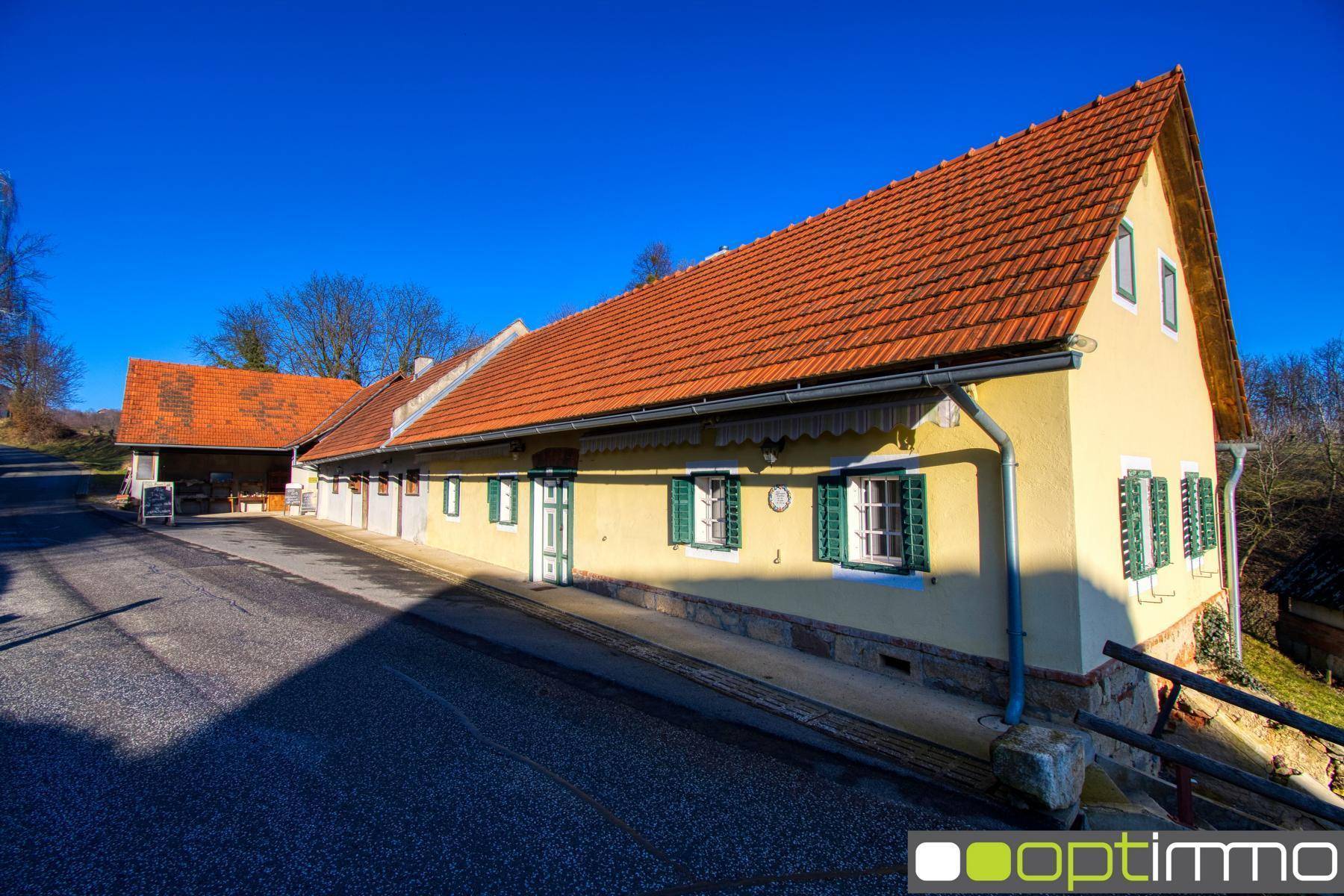 Langes, traditionelles Gebäude mit gelber Fassade, roten Ziegeldächern und grünen Fensterläden.
