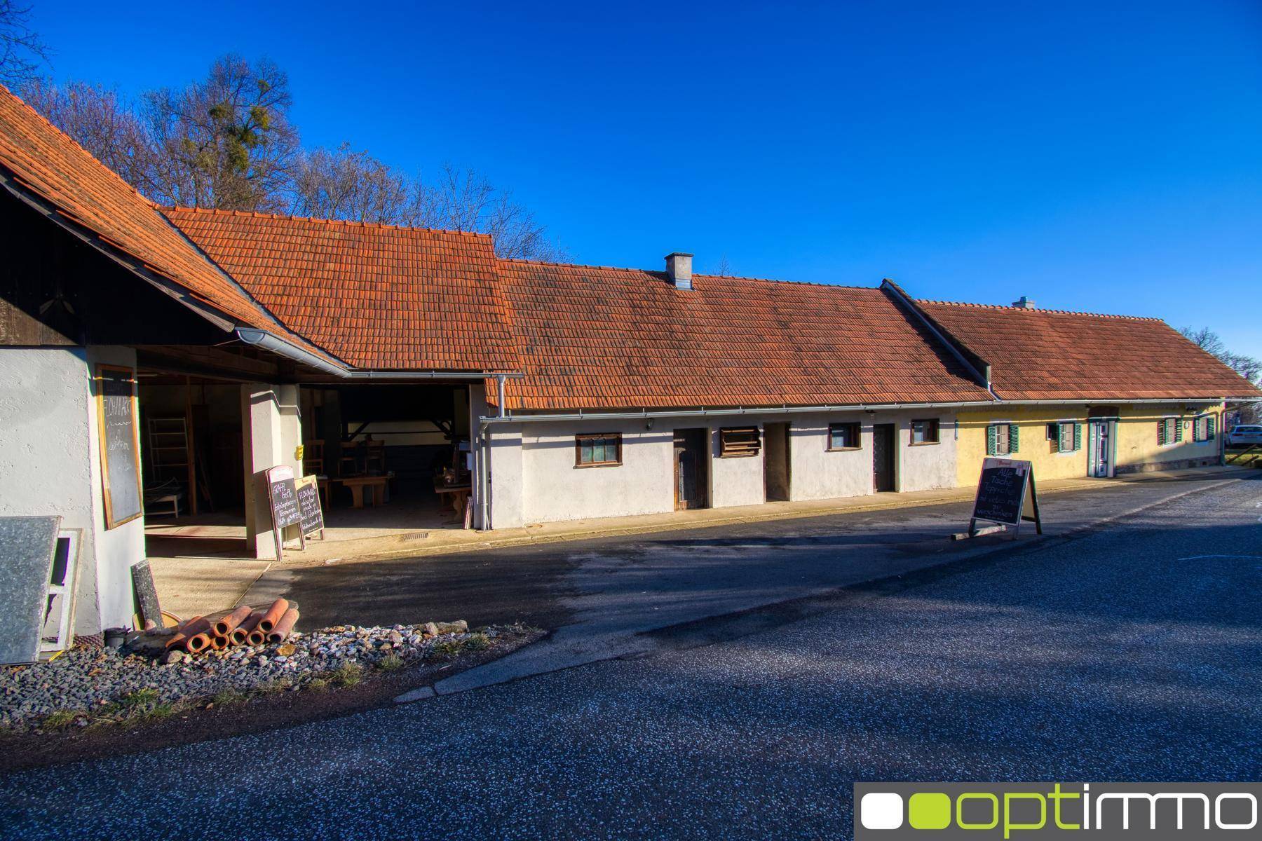 Ländliches Anwesen mit mehreren Gebäuden, roten Ziegeldächern und einer breiten Zufahrt.