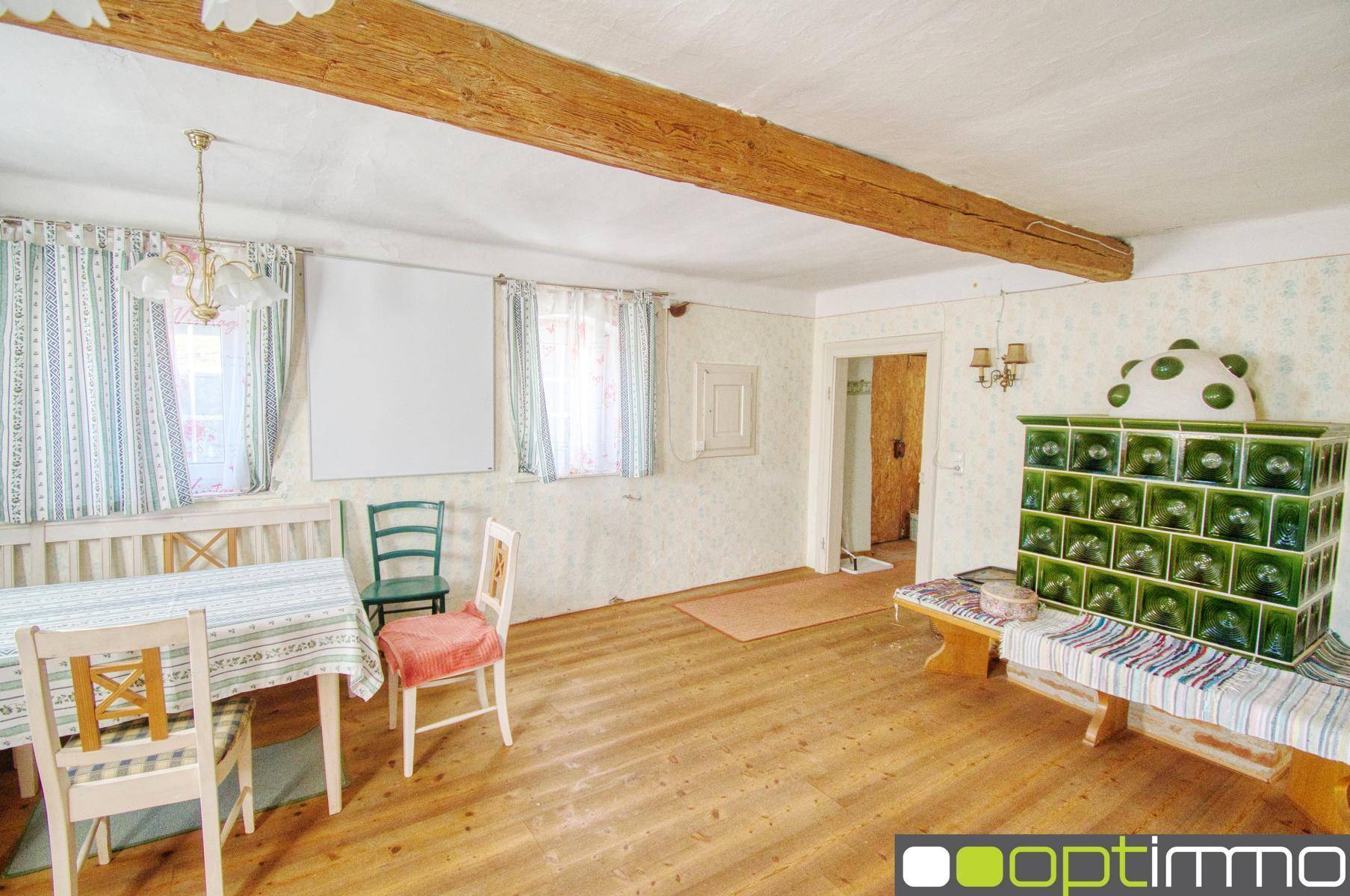 Gemütlicher Wohn-Essbereich mit Holzbalken, Parkettboden und traditionellem Kachelofen.