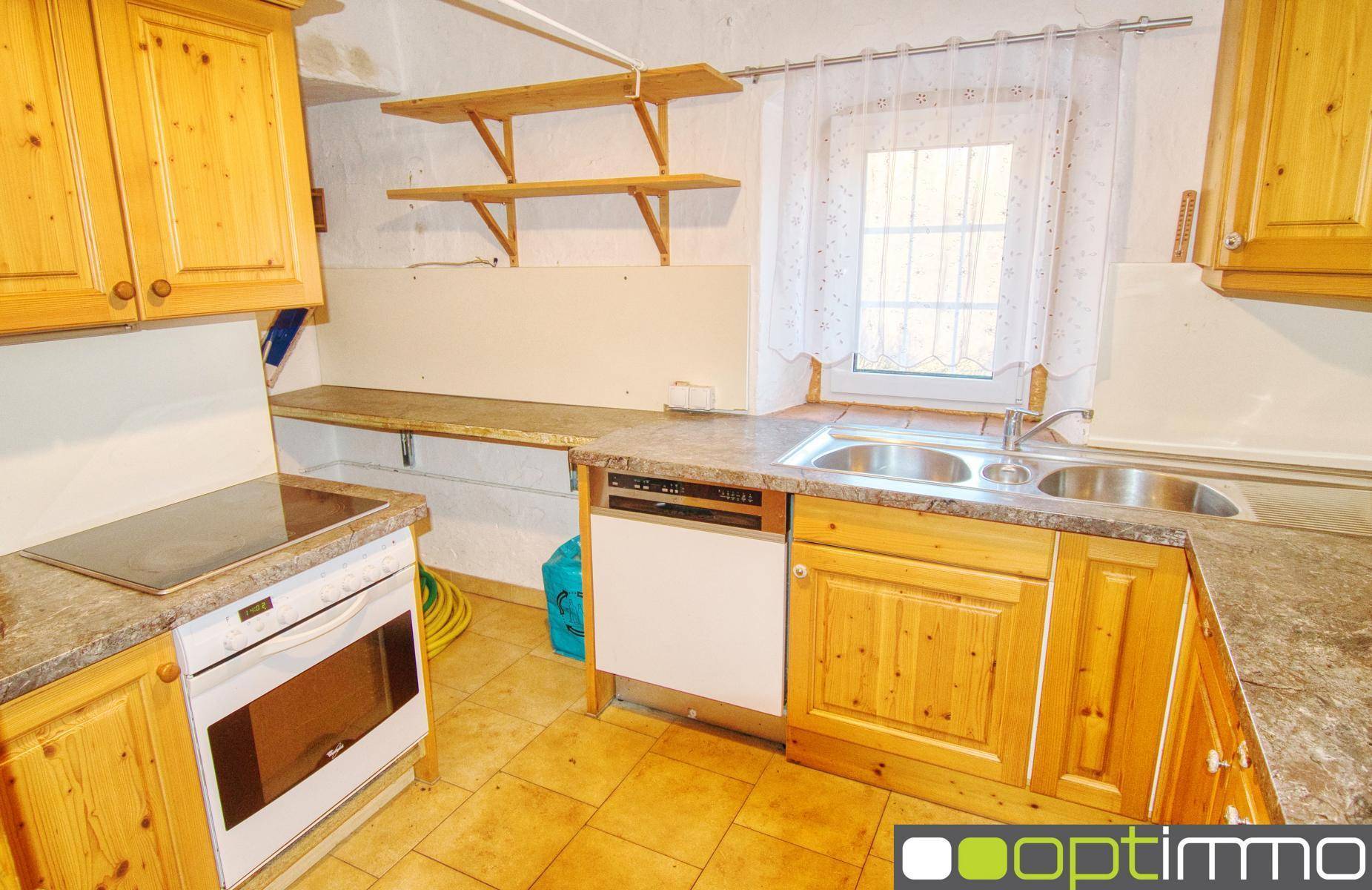 Rustikale Küche mit Holzschränken, Fliesenboden und integriertem Geschirrspüler.