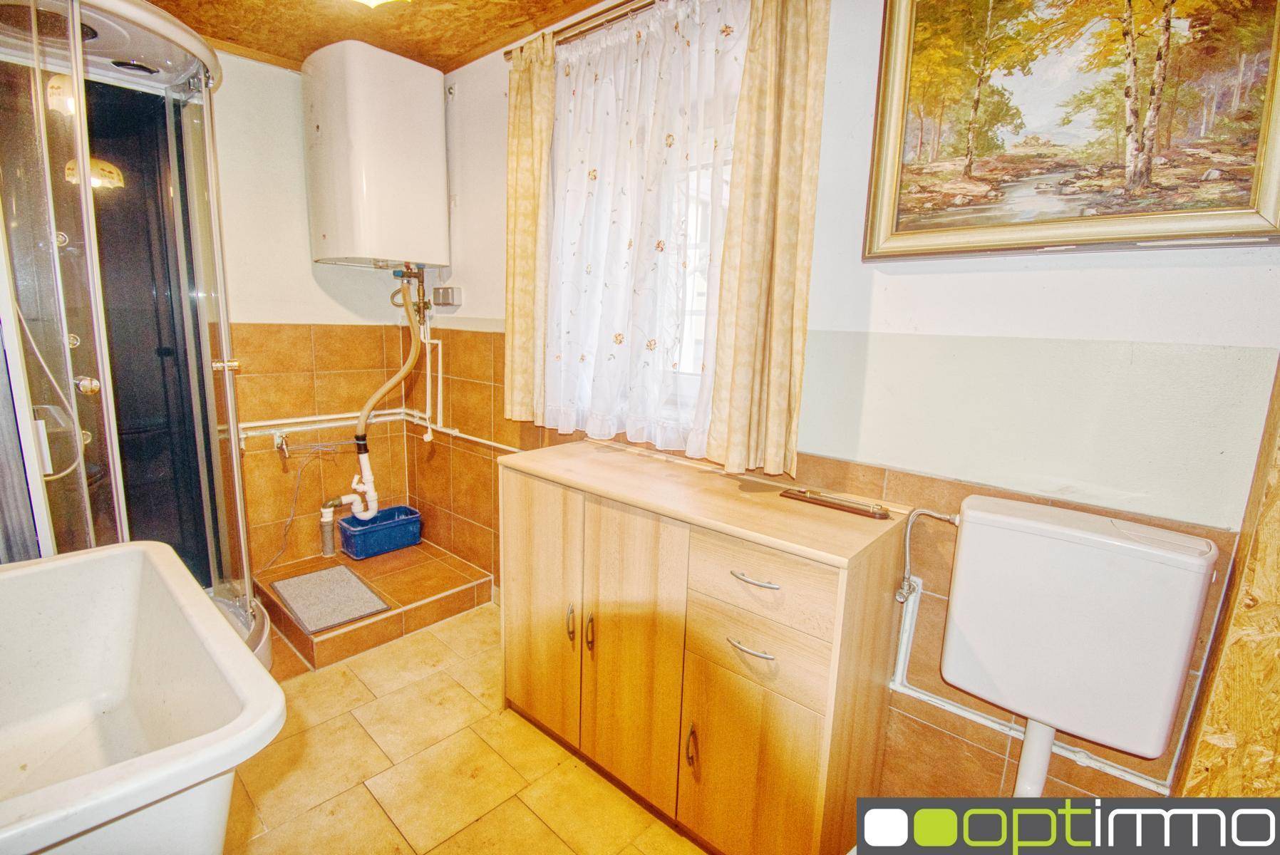 Einfaches Badezimmer mit Duschkabine, WC und Fliesen in warmen Brauntönen.