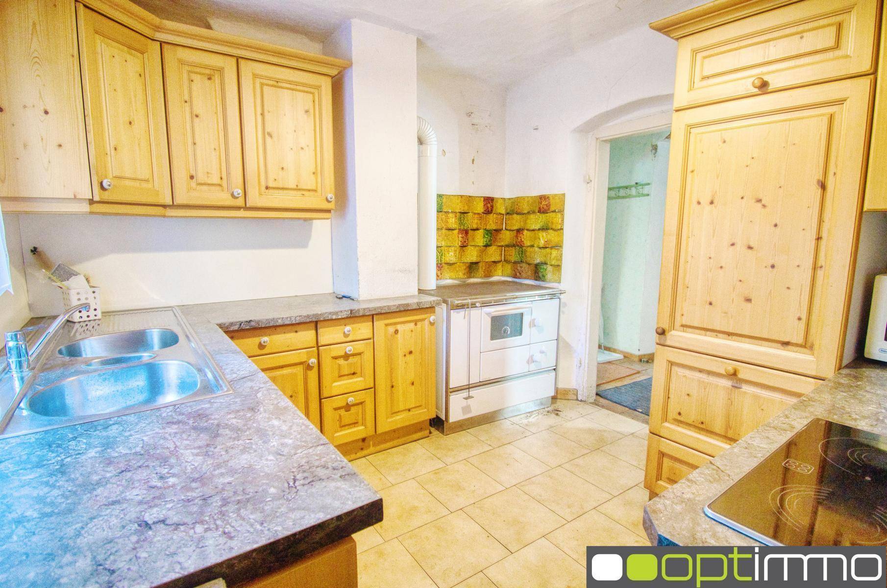 Traditionelle Holzküche mit Fliesenboden, Doppelspüle und einem historischen Herd.