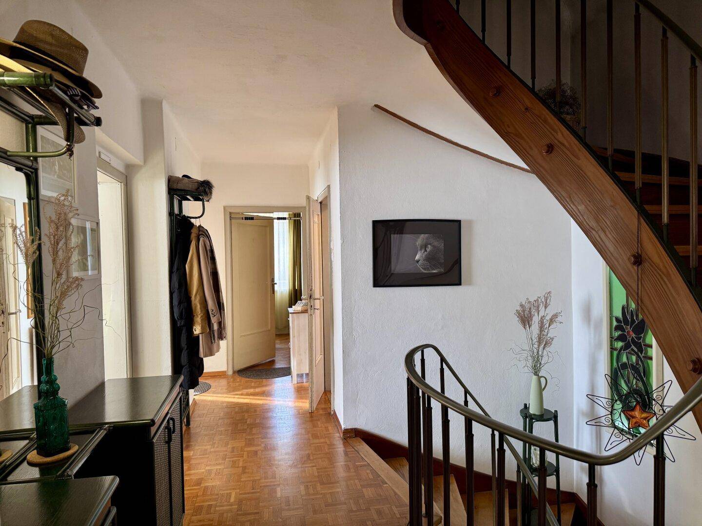 Geräumiger Flur mit Holztreppe, Garderobe und hellem Parkettboden.