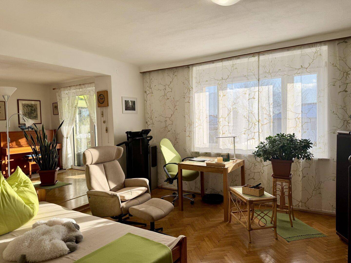 Helles Wohnzimmer mit Schreibtisch, bequemen Möbeln und Blick ins Grüne.