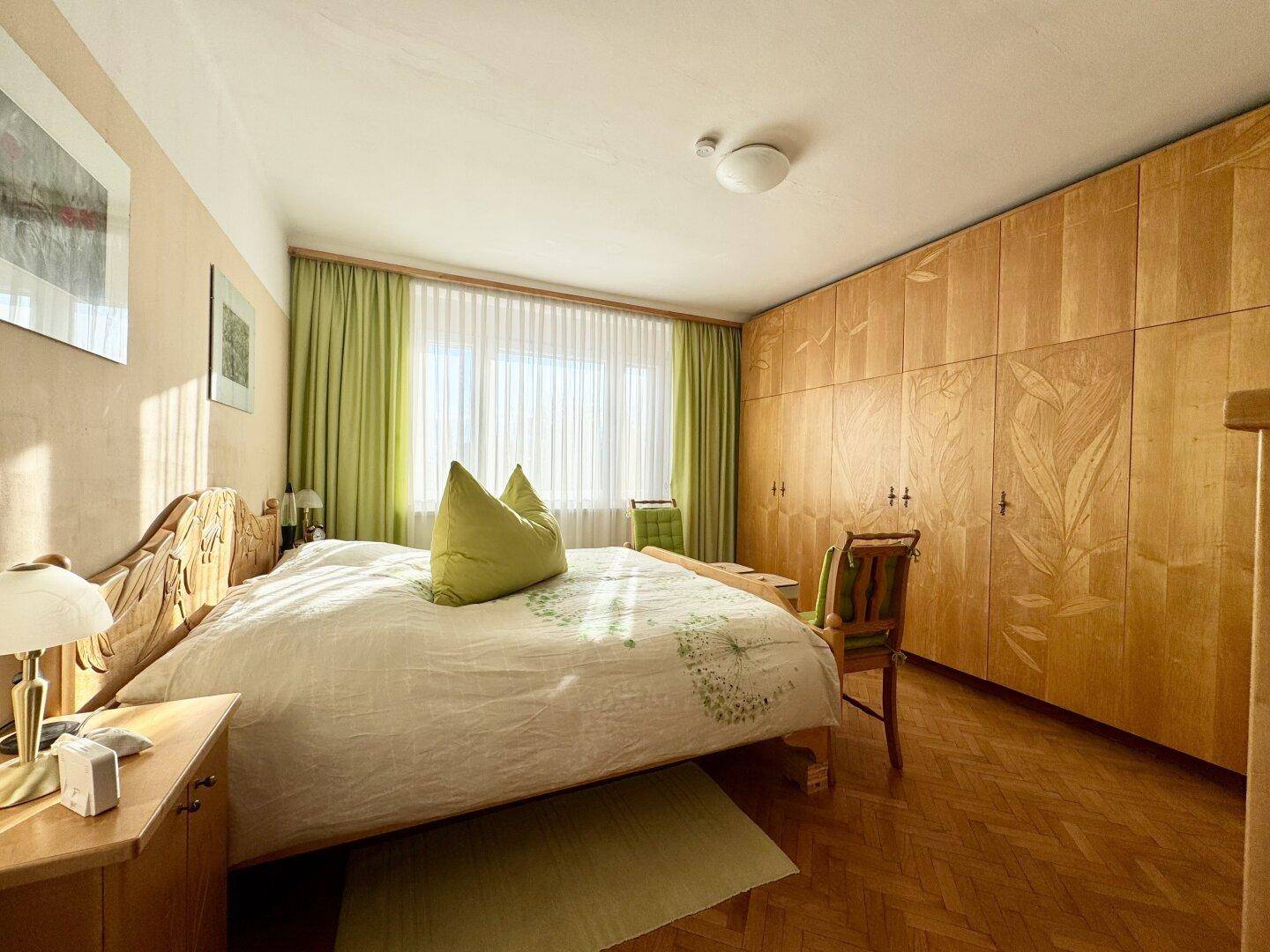 Helles Schlafzimmer mit Doppelbett, Einbauschränken und Parkettboden.