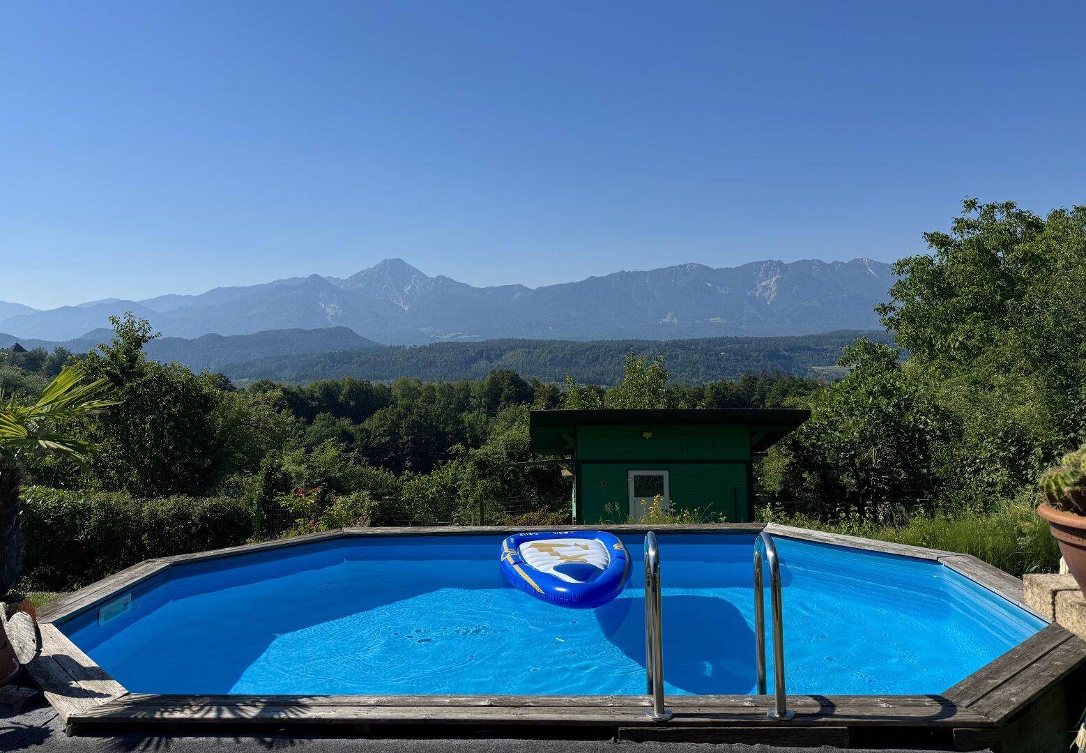 Erfrischender Pool im Garten mit aufblasbarem Boot und atemberaubendem Bergblick.