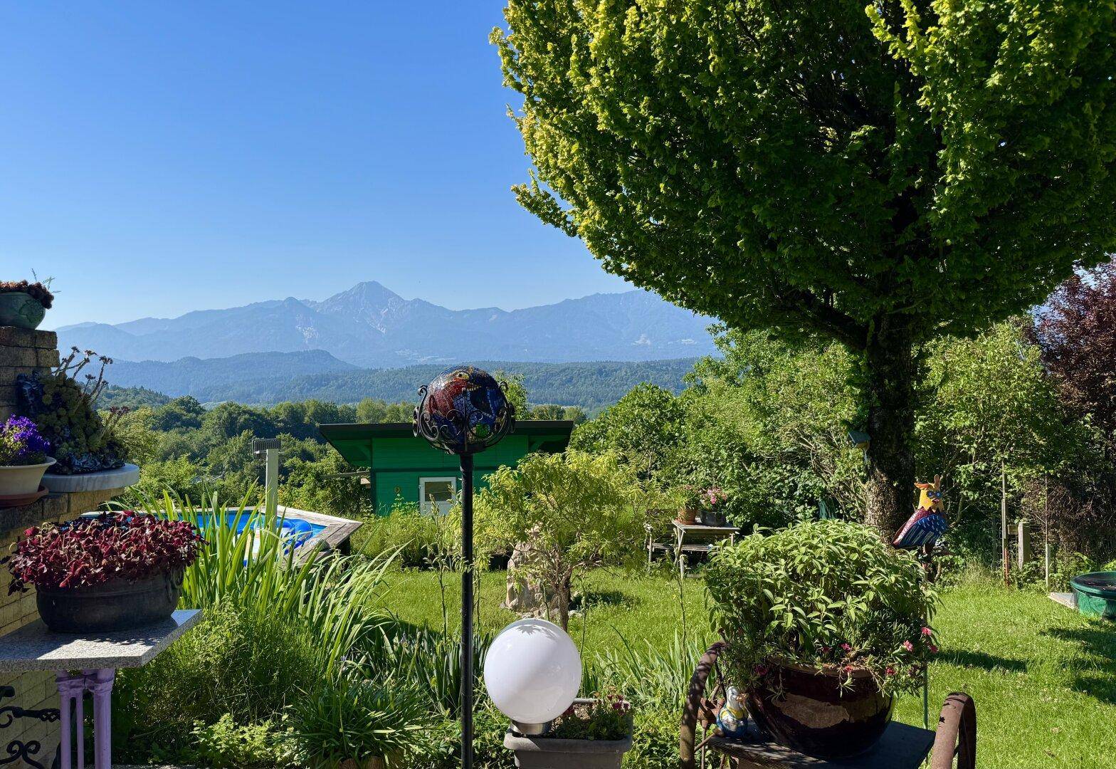 Detailansicht des Gartens mit üppiger Bepflanzung, Dekoration und weitem Bergblick.
