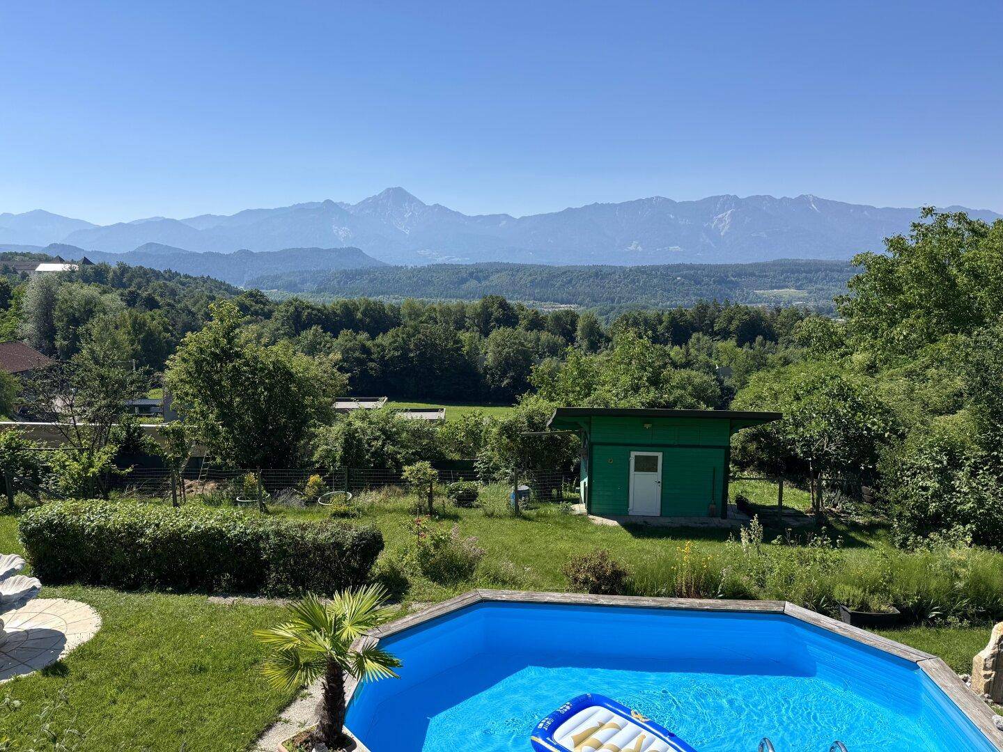 Erholsamer Poolbereich im Garten mit Palmen und weitem Blick auf die Berglandschaft.