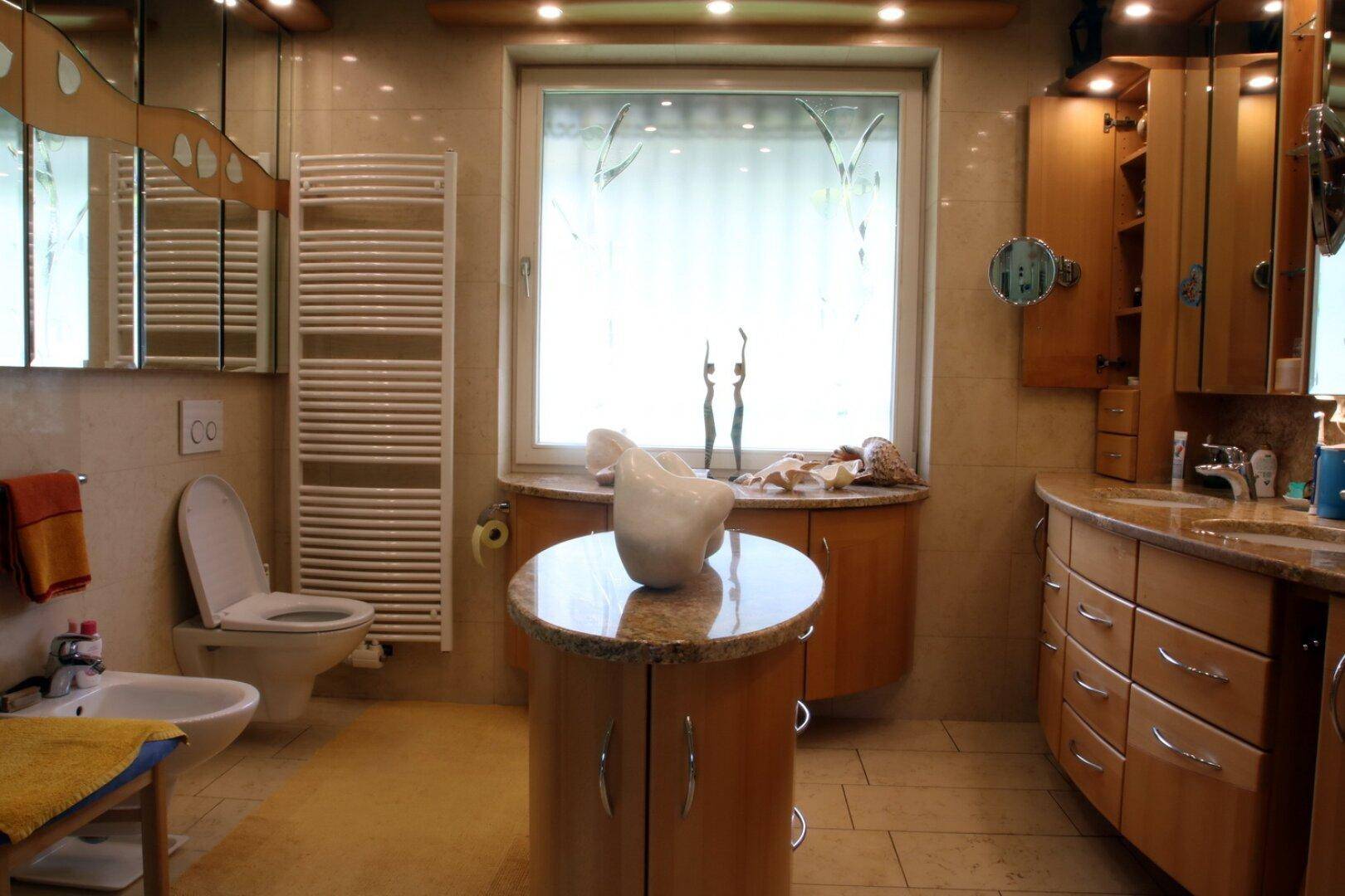 Geräumiges Badezimmer mit Doppelwaschbecken, Badewanne, Bidet und Fenster.