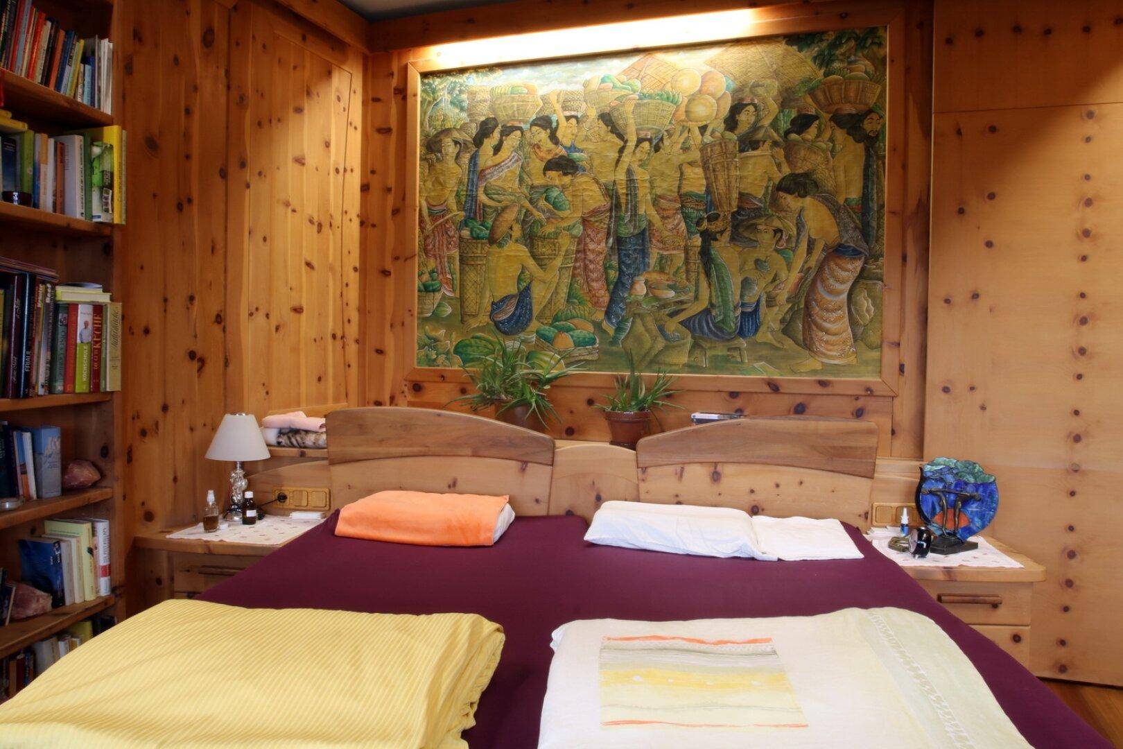 Gemütliches Schlafzimmer mit Holzvertäfelung, Einbauregalen und großem Wandgemälde.