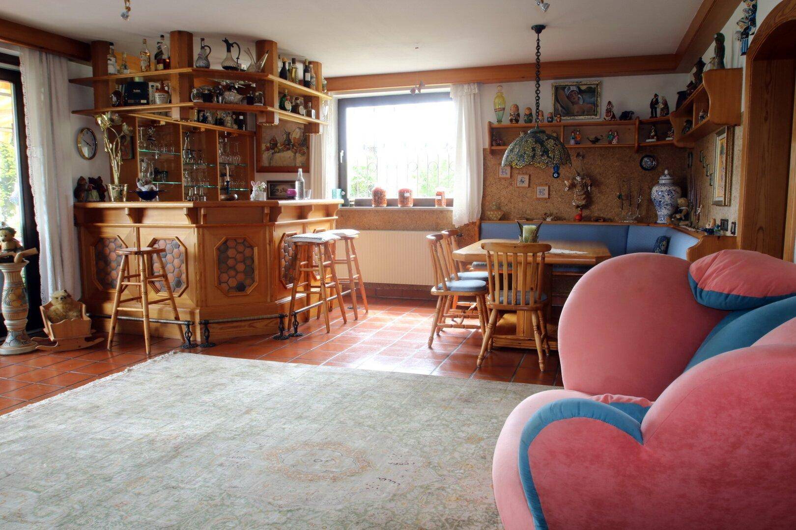 Wohnzimmer mit rustikaler Holzbar, Essecke und gemütlicher Sitzecke in warmen Farben.
