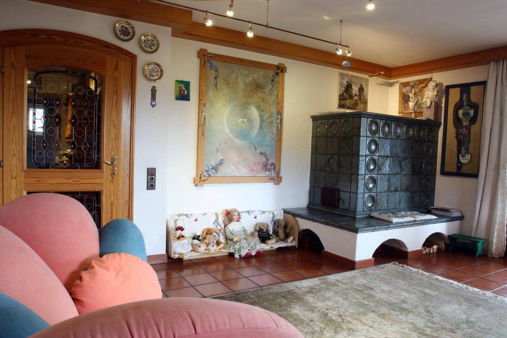 Wohnzimmer mit großem Kachelofen, Kunstwerken und gemütlicher Sitzecke.