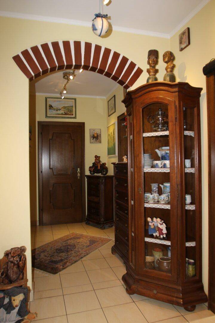 Eingangsbereich mit traditionellen Holzmöbeln, Fliesenboden und dekorativem Bogen.