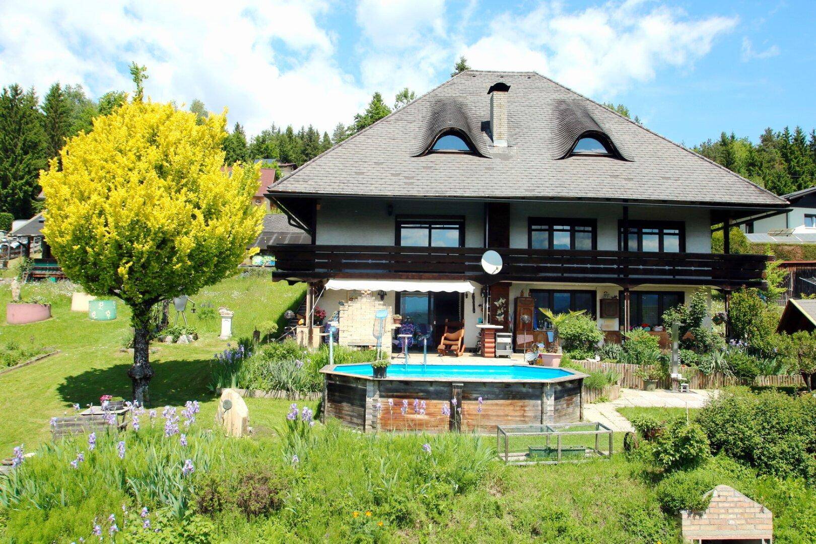 Einfamilienhaus mit großem Garten, oberirdischem Pool und üppiger Vegetation unter blauem Himmel.
