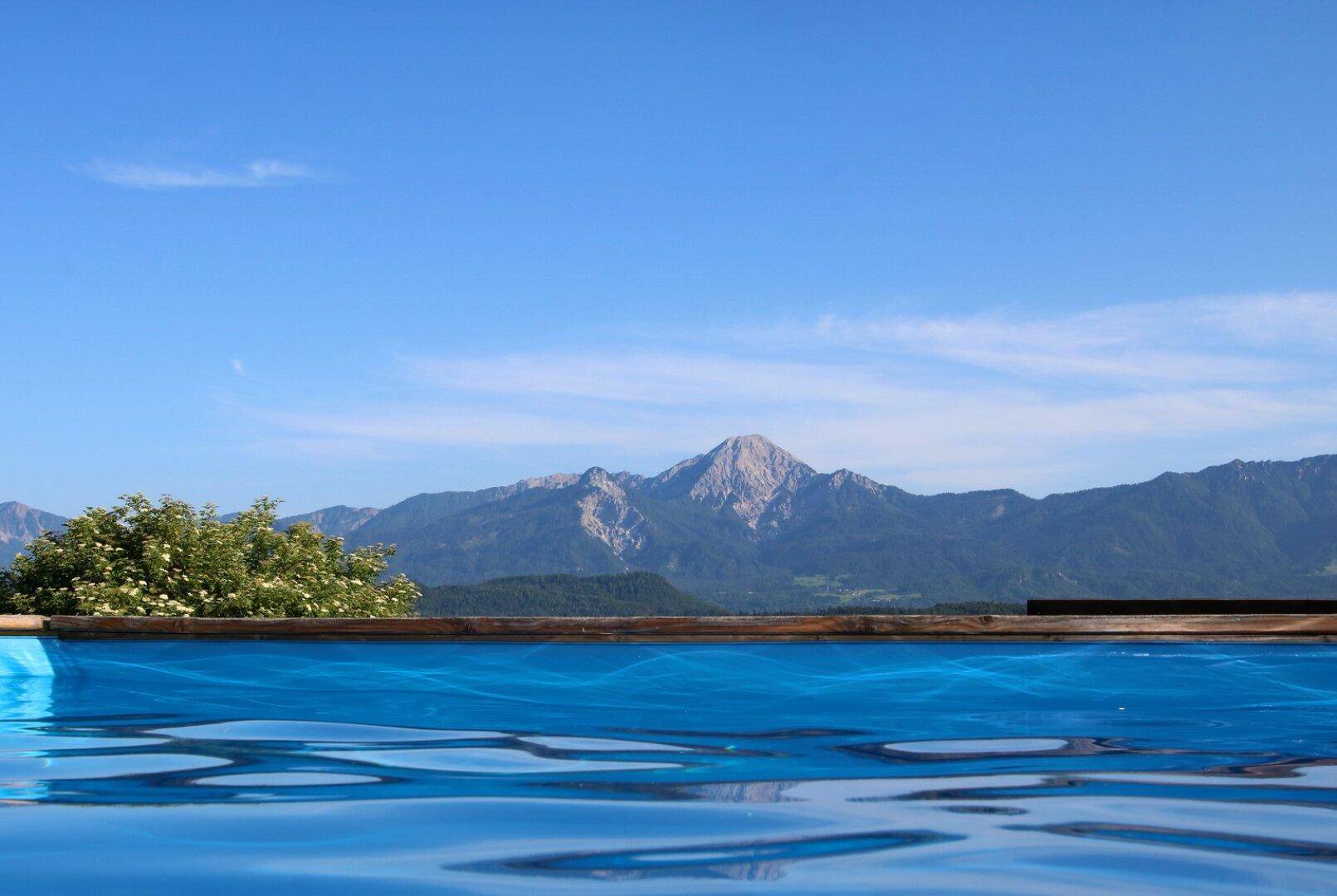 Erfrischender Pool mit Panoramablick auf die majestätische Berglandschaft unter blauem Himmel.