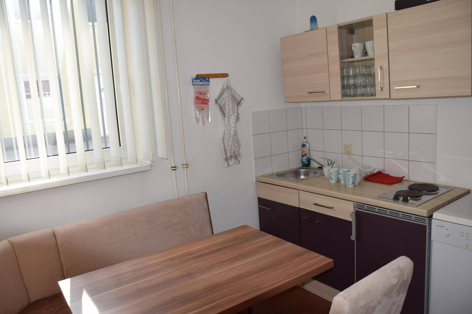 Kleine Küchenzeile mit Esstisch und Sitzbank, ausgestattet mit Spüle und Kochfeld.