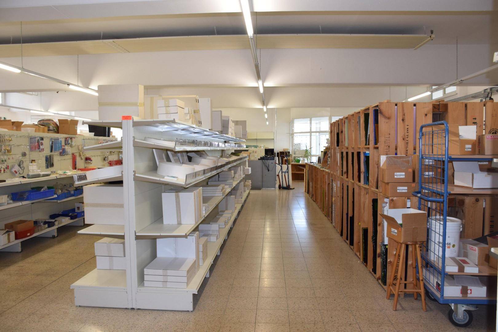 Langer Gang in einem Lagerraum mit beidseitigen Regalen, gefüllt mit Kartons und Waren.