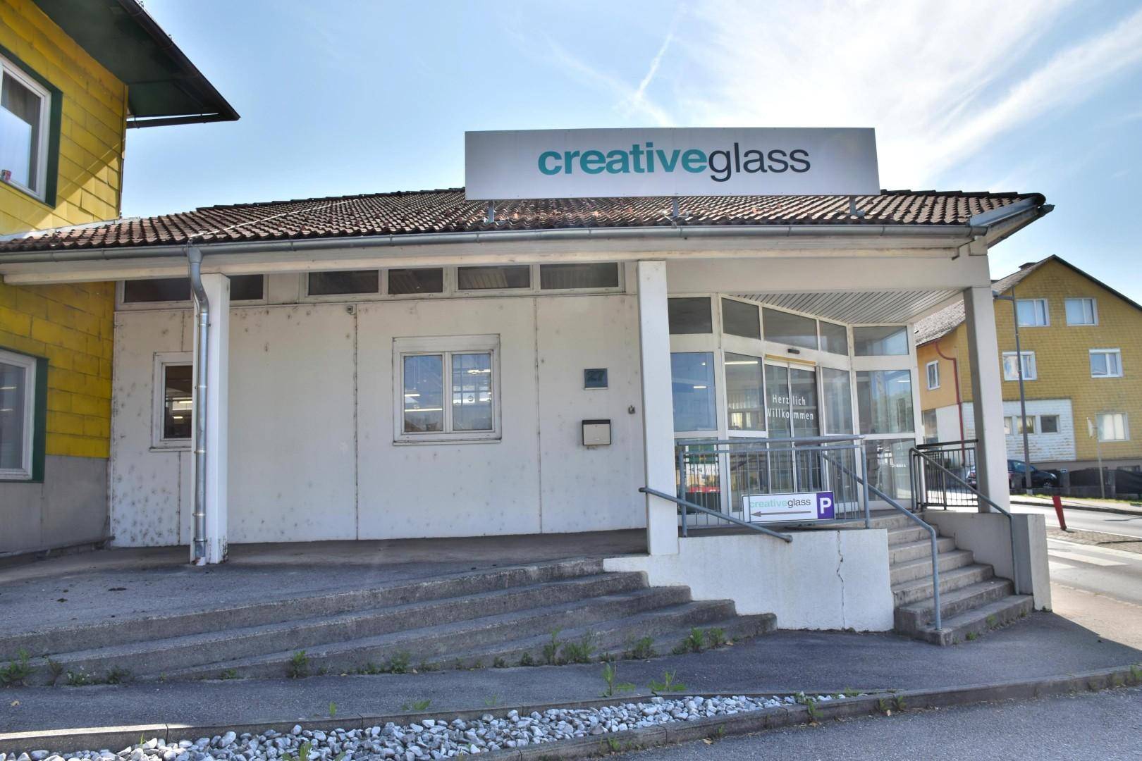 Vorderansicht des Geschäftsgebäudes mit 'creativeglass'-Schild, Eingang und angrenzender Straße.