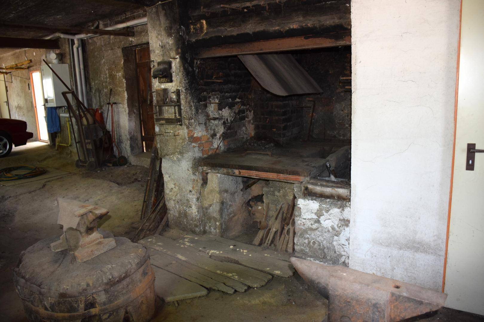 Großer alter Ofen oder Kamin in einem rustikalen Raum, möglicherweise einer Werkstatt oder Keller.