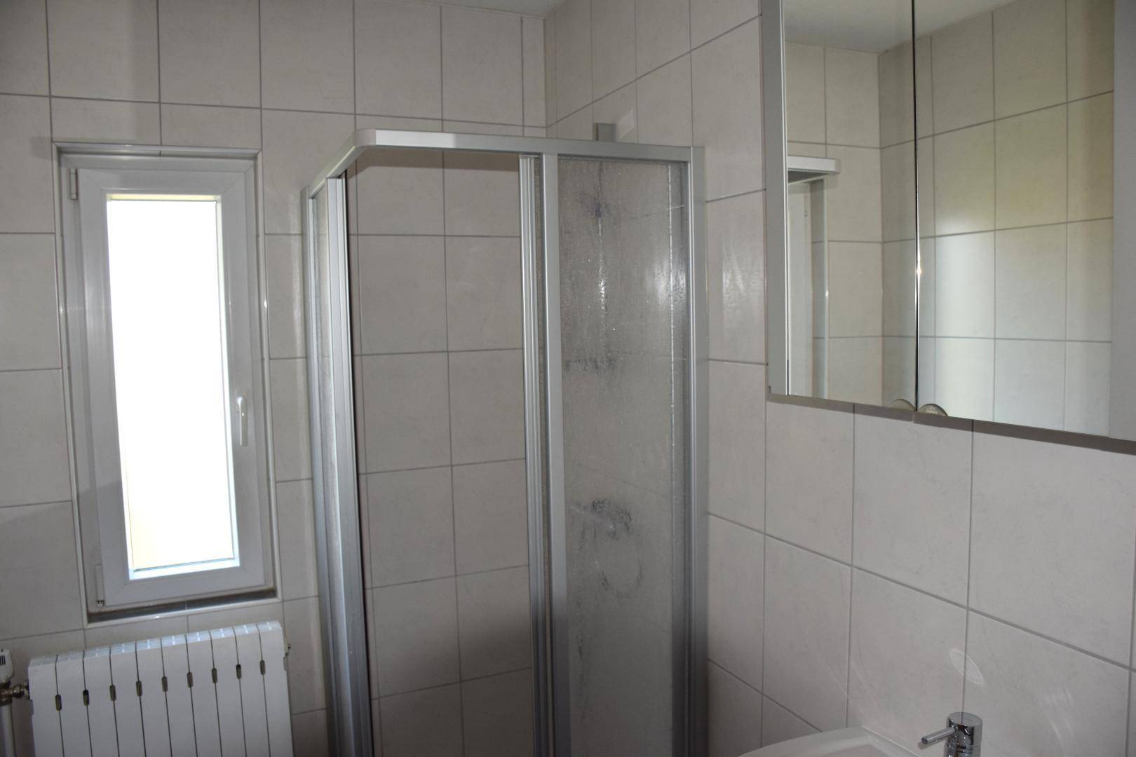 Funktionales Badezimmer mit Duschkabine, Waschbecken und Spiegelschrank.