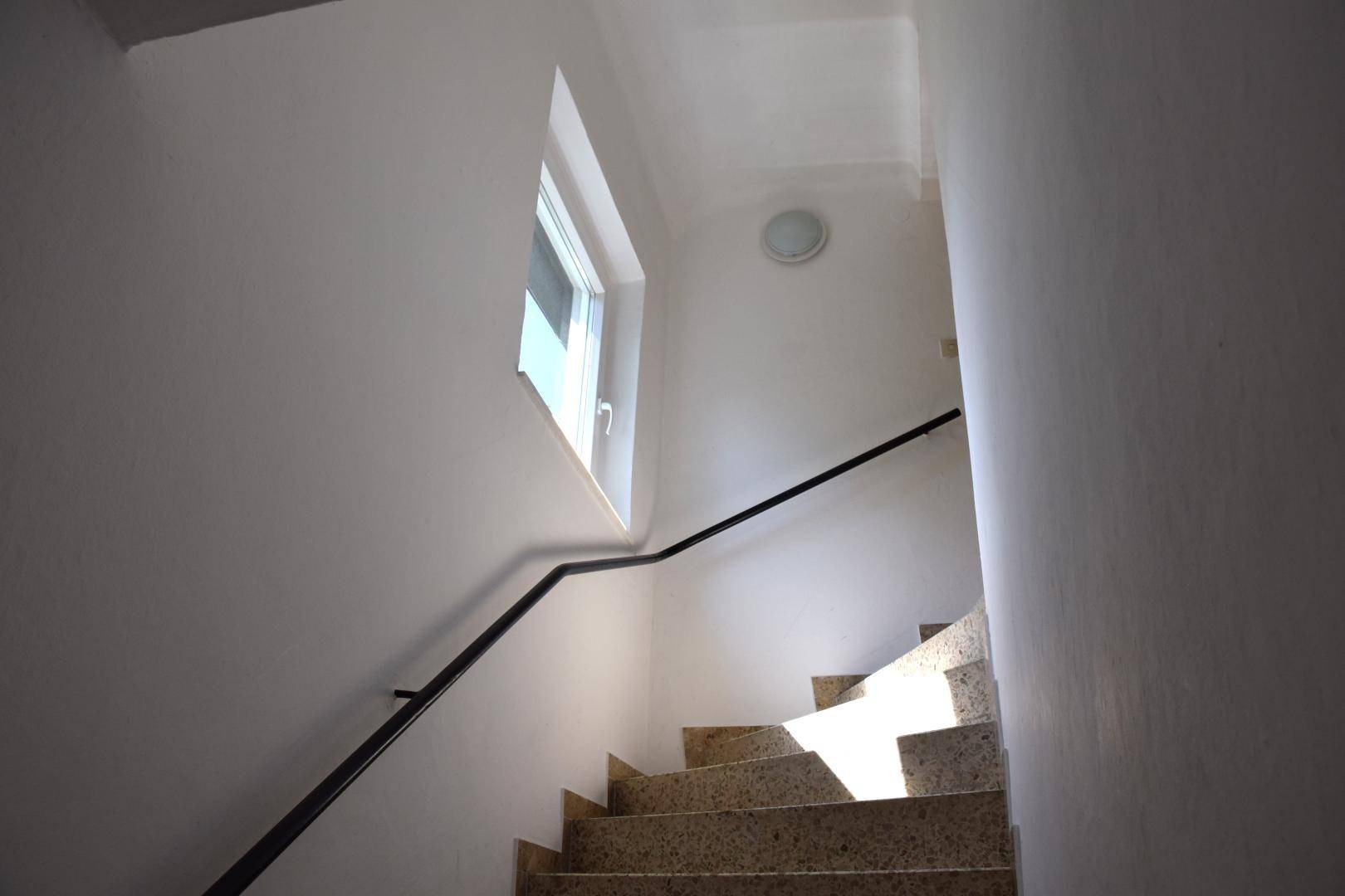 Heller Treppenaufgang mit Granitstufen und Fenster für natürliches Licht.