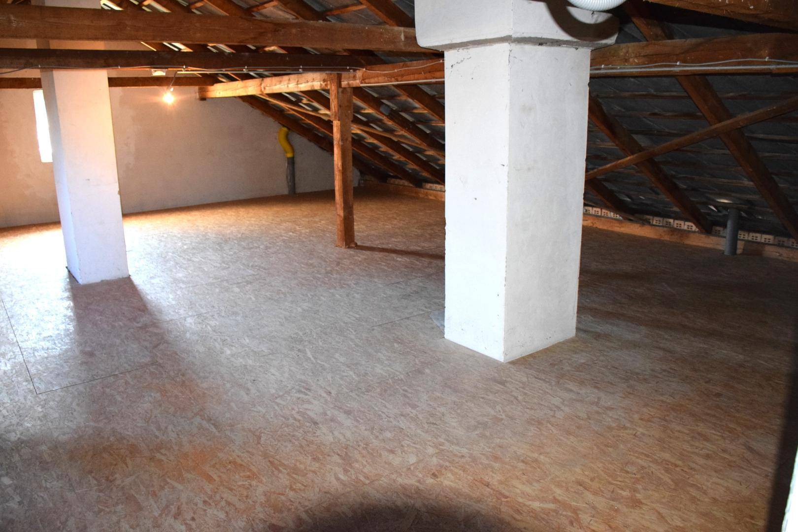 Ausbaufähiger Dachboden mit sichtbaren Holzbalken und OSB-Plattenboden.