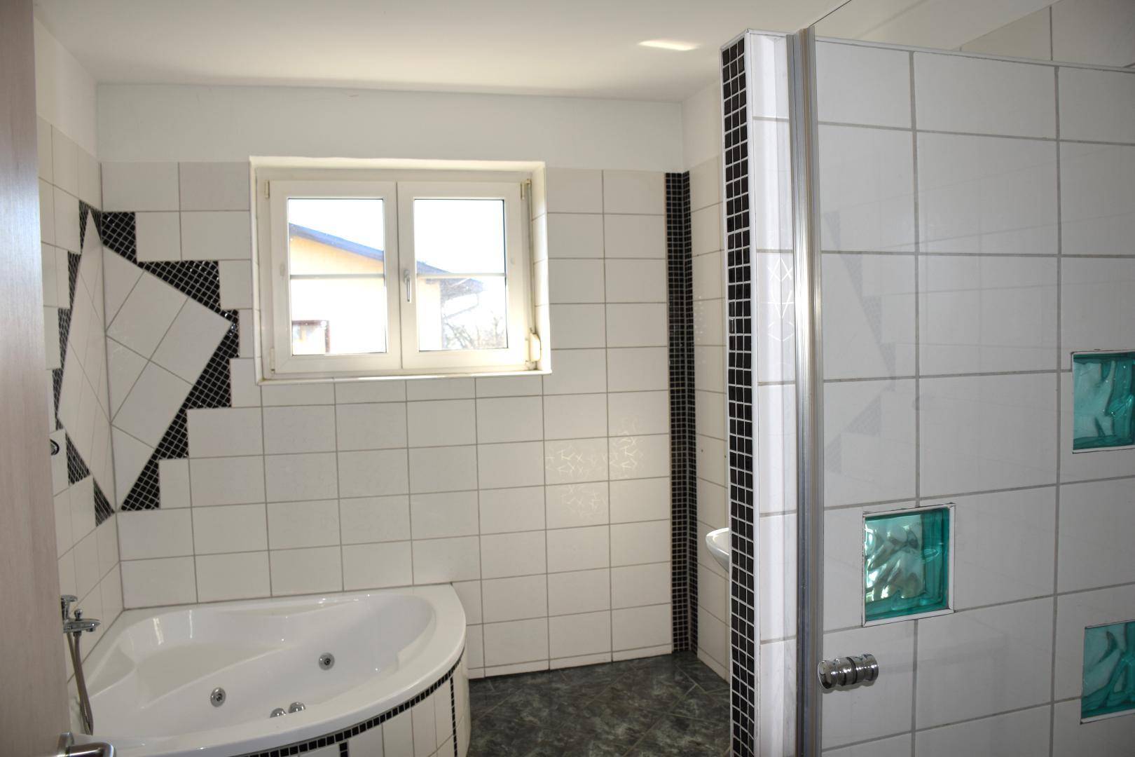 Modern gefliestes Badezimmer mit Eckbadewanne, Whirlpoolfunktion und Duschbereich.