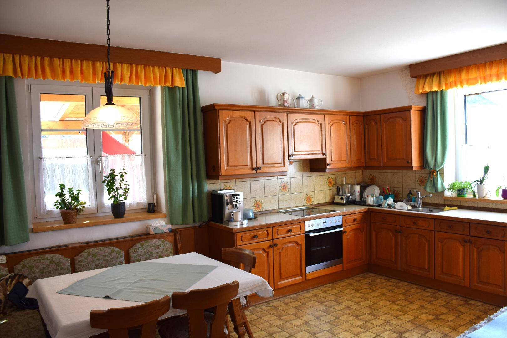 Gemütliche Wohnküche im traditionellen Stil mit Holzeinbauten und Essbereich am Fenster.