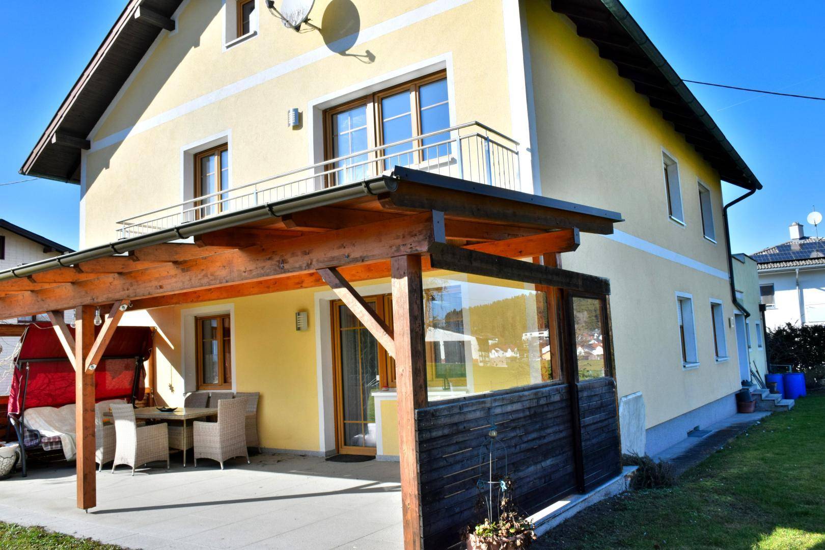 Detailansicht der überdachten Terrasse mit seitlichem Sichtschutz und Sitzgelegenheiten.