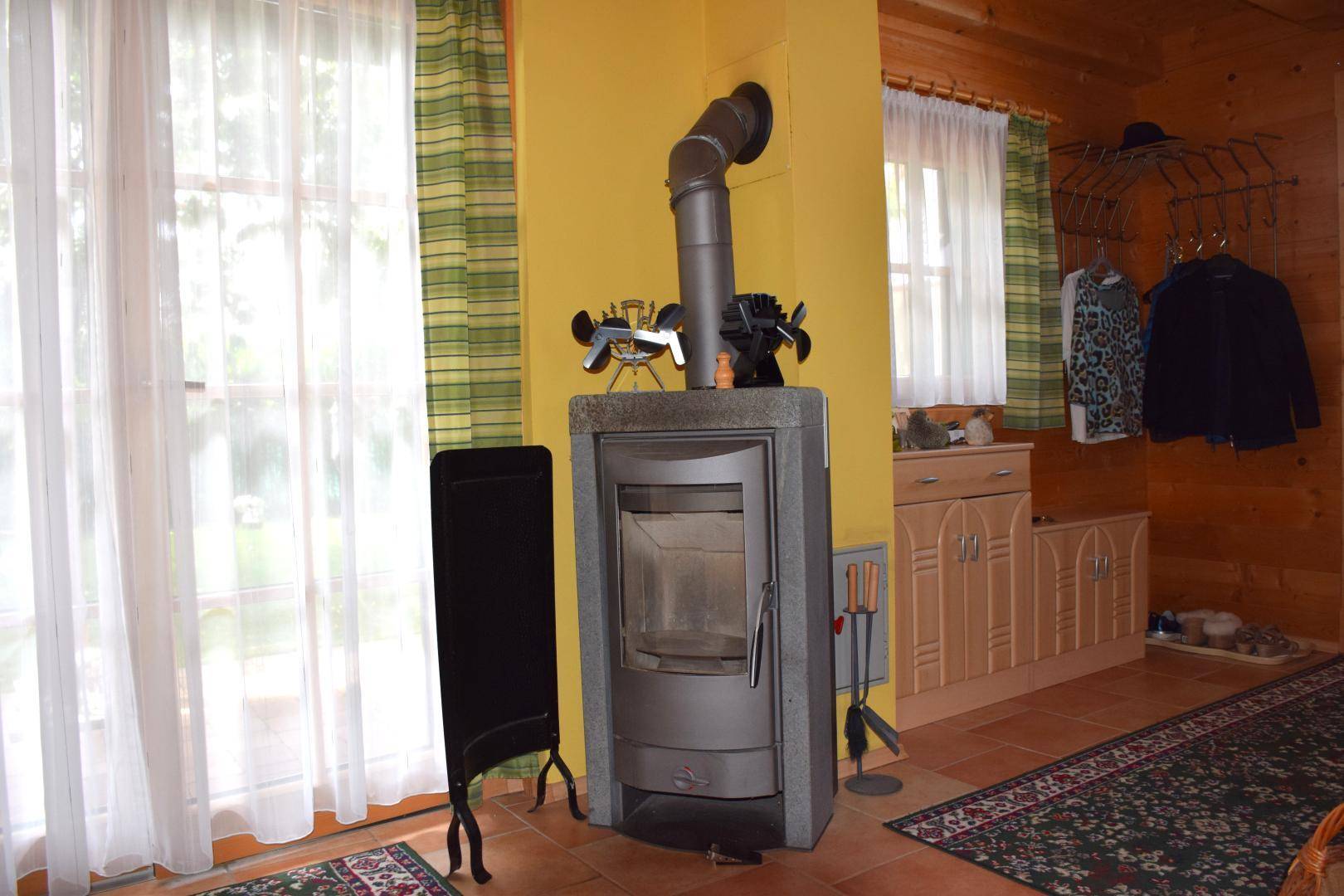 Gemütlicher Kaminofen im Wohnbereich mit Fliesenboden und großen Fenstern.