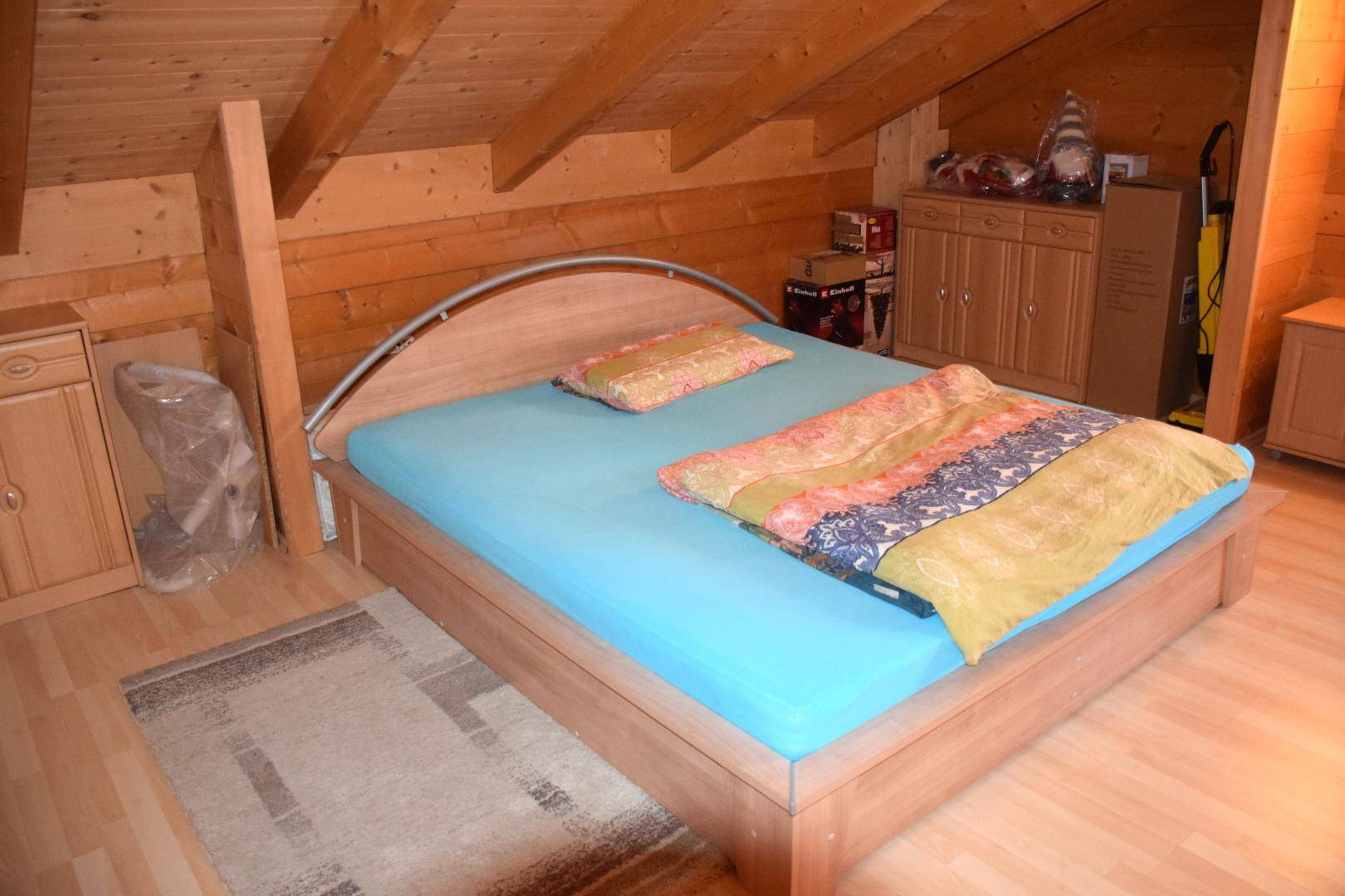 Schlafzimmer im Dachgeschoss mit Holzboden, schrägen Wänden und einem Doppelbett.
