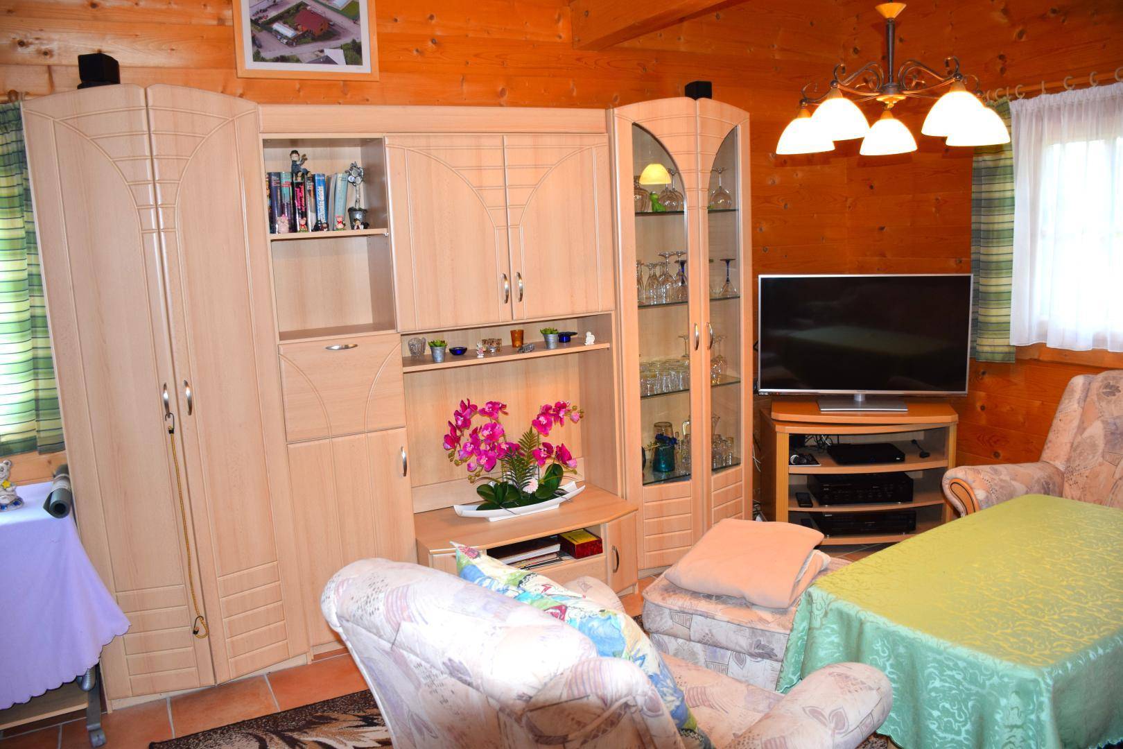 Wohnzimmer mit Holzmöbeln, Fernseher und einer gemütlichen Sitzecke.