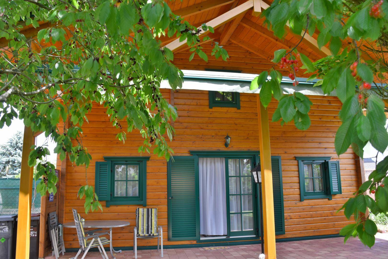 Überdachte Terrasse am Holzhaus mit Gartenmöbeln und Zugang zum Innenbereich.