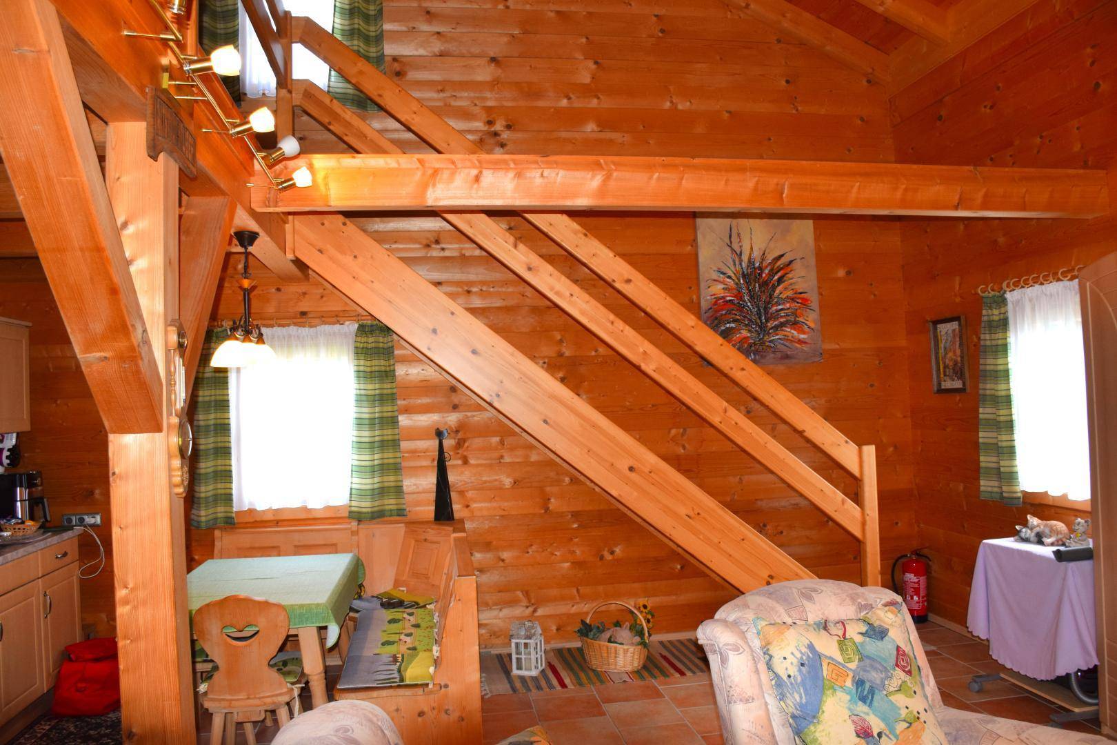 Geräumiger Wohn-Essbereich mit Holztreppe, gemütlicher Sitzecke und viel Tageslicht.