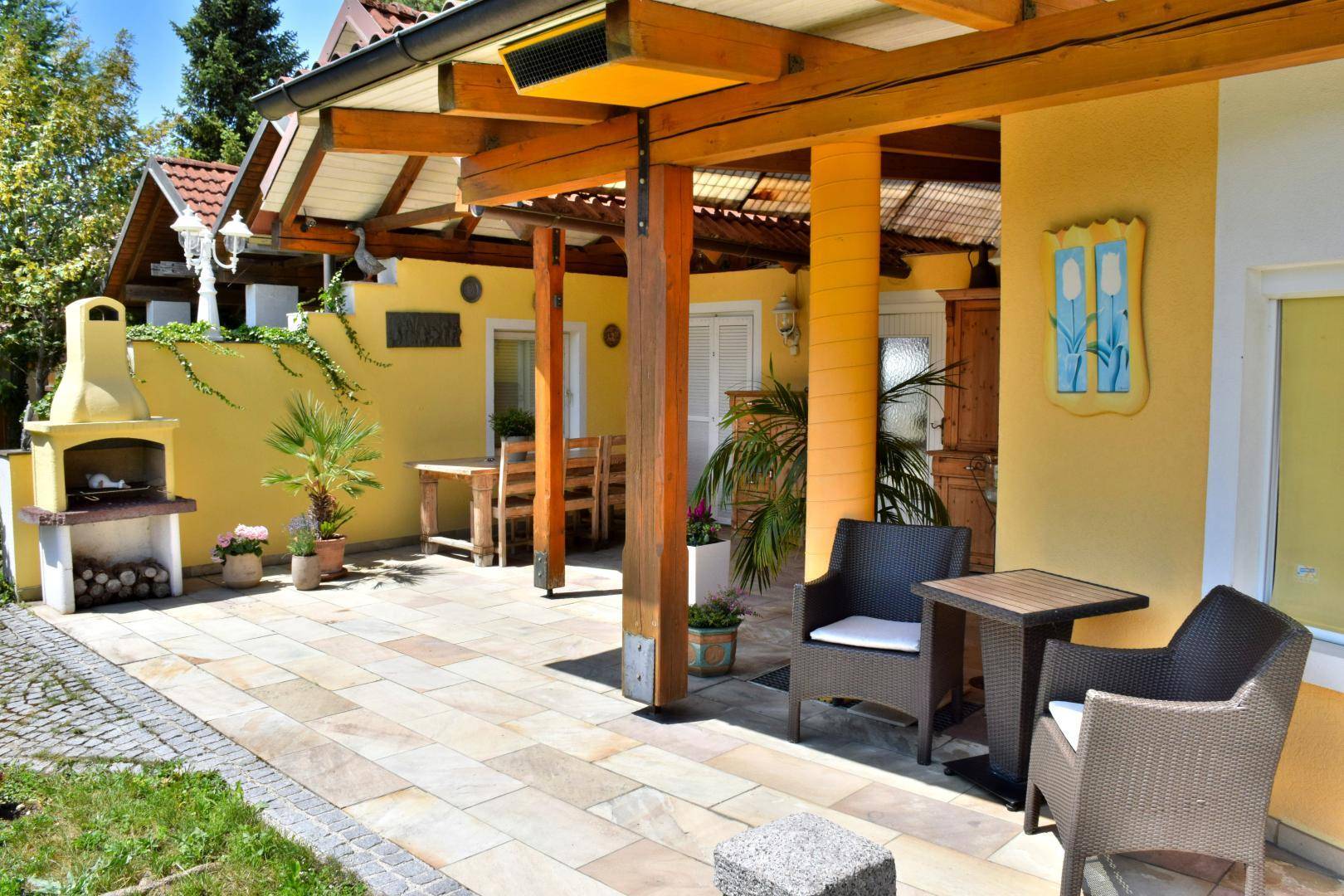 Geräumige Terrasse mit Fliesenboden, bequemen Sitzgelegenheiten und einem gemauerten Grillbereich.