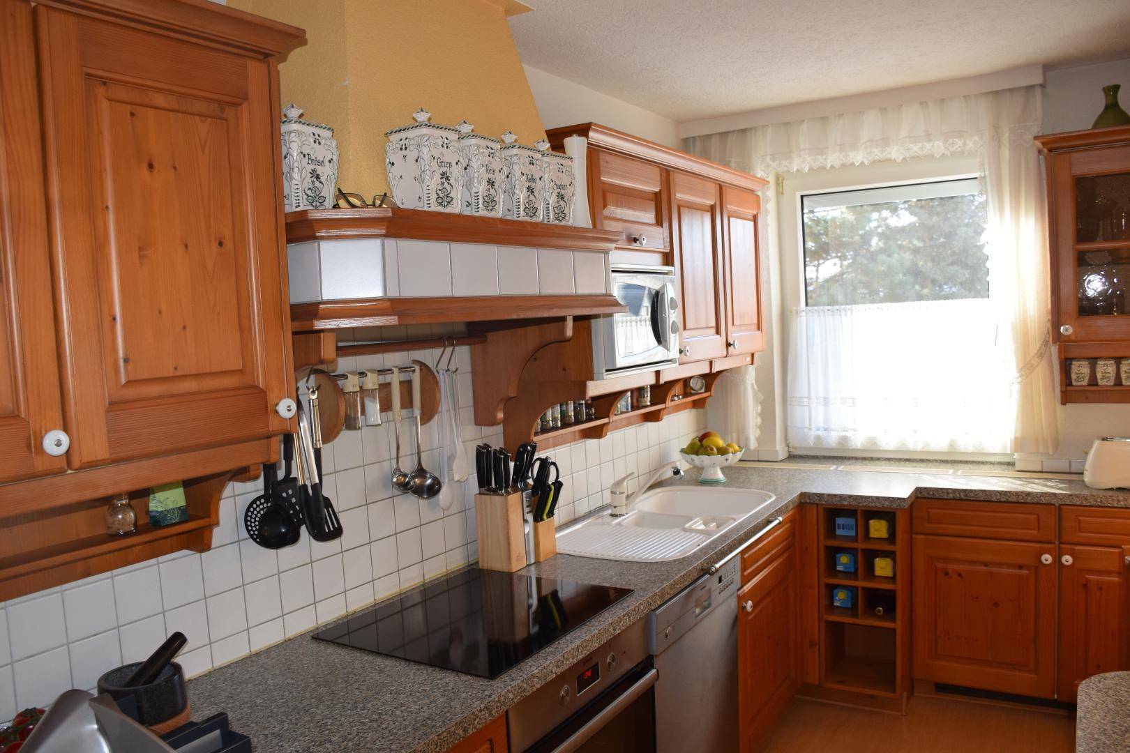 Traditionelle Holzküche mit Einbauschränken, weißem Fliesenspiegel und modernen Küchengeräten.