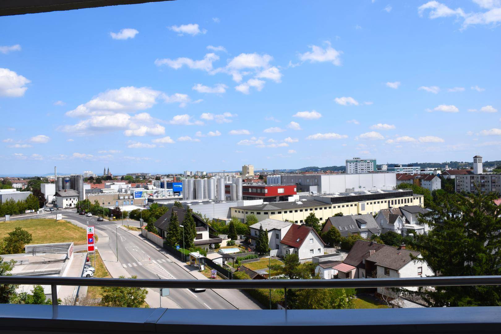 Weitläufiger Blick über die Stadt und umliegende Gebäude unter blauem Himmel.