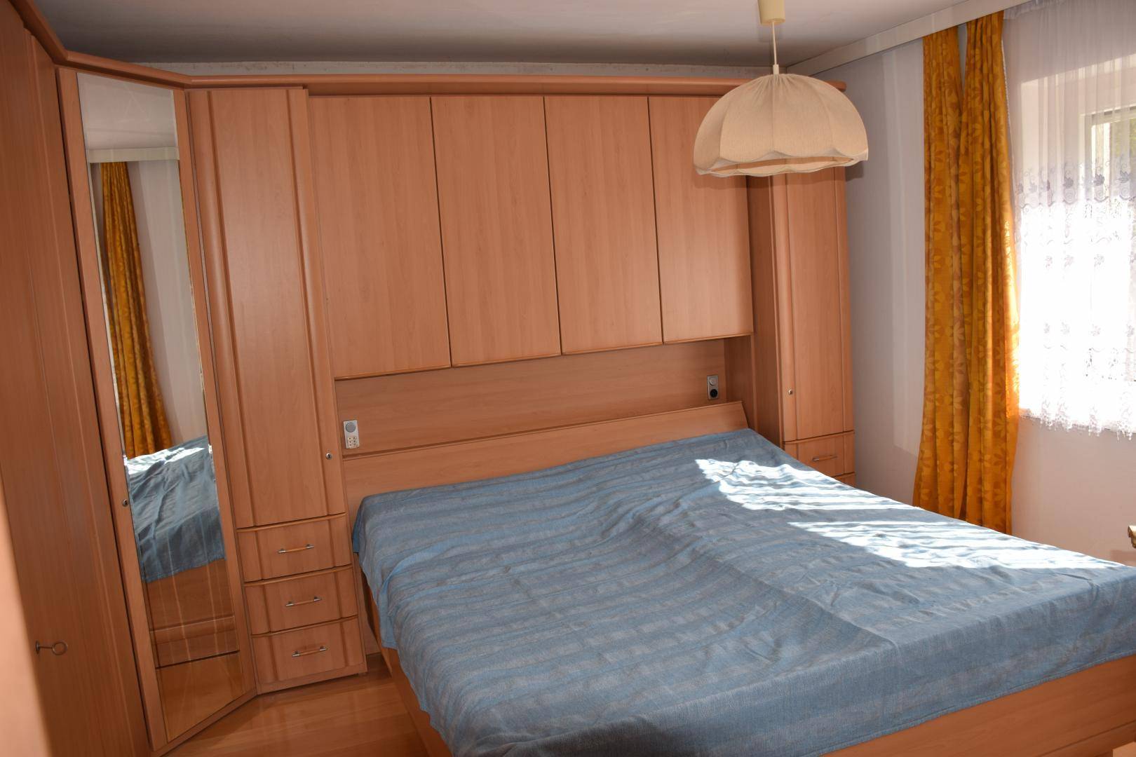 Schlafzimmer mit Doppelbett, Einbauschränken und Fenster, hell und funktional eingerichtet.