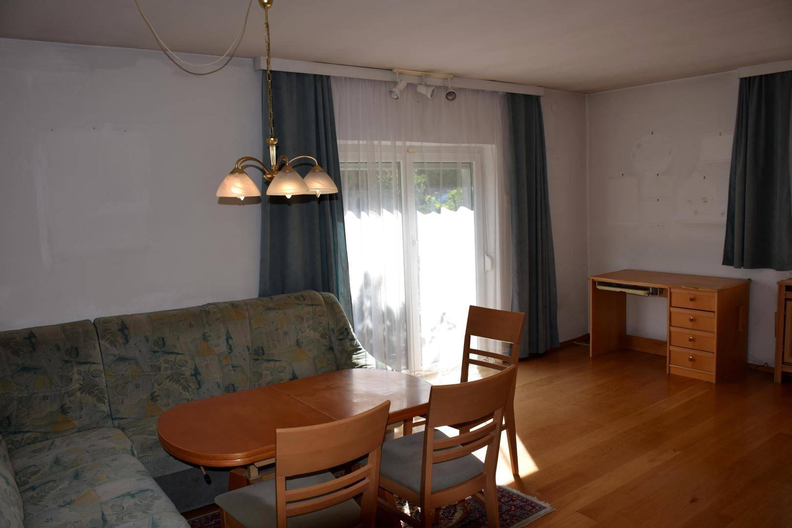 Heller Wohn-Essbereich mit Holzboden, Esstisch, Sofa und Zugang zum Außenbereich.