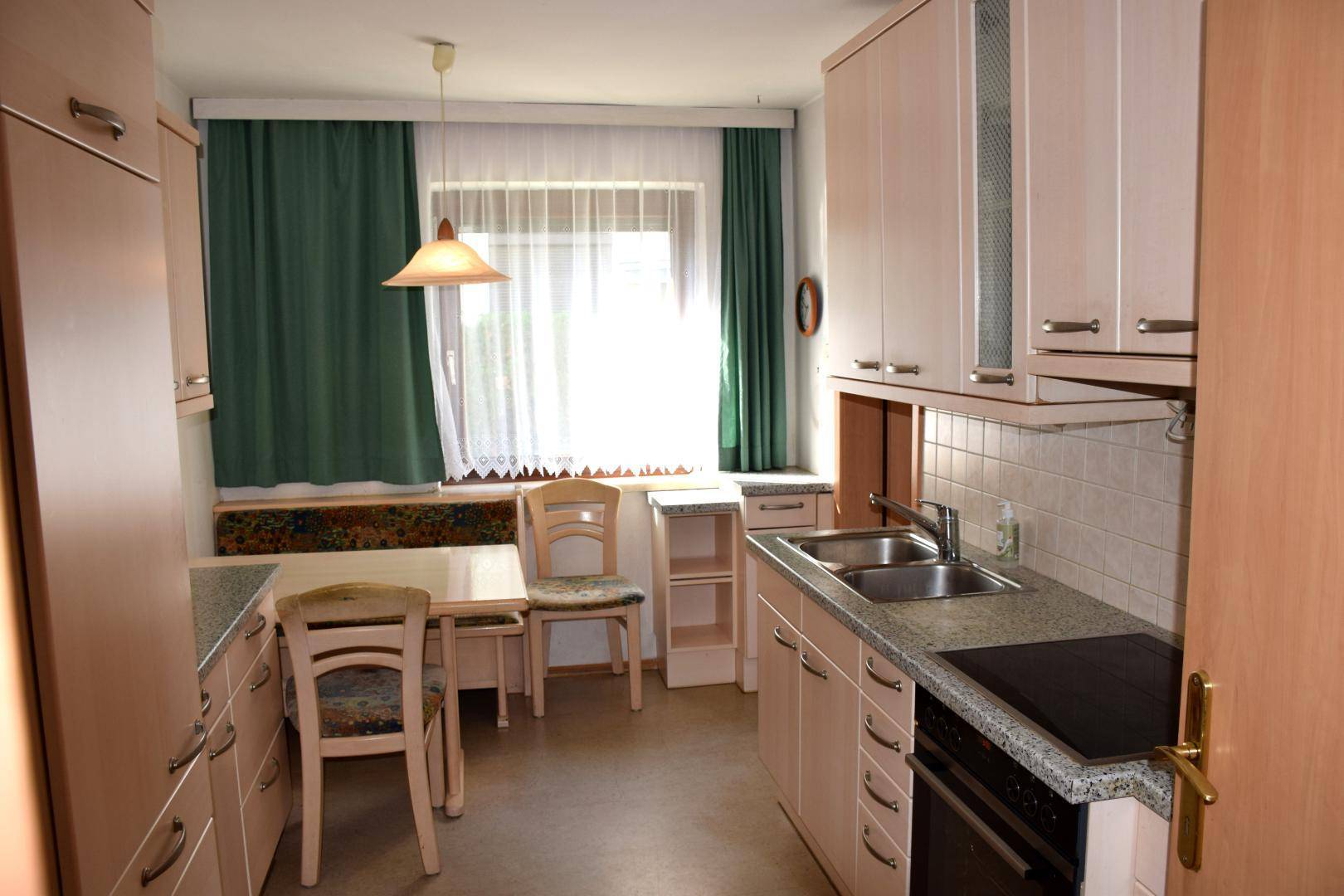 Helle Wohnküche mit hellen Holzschränken, Essbereich und Fenster, funktional ausgestattet.