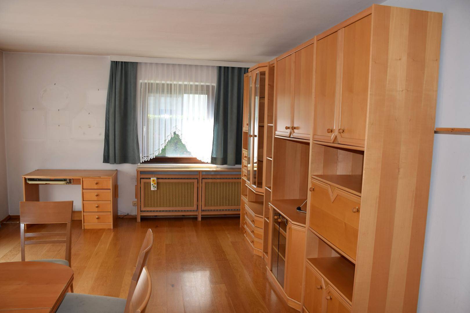 Geräumiges Wohnzimmer mit Holzmöbeln, Schreibtisch und Fenster, hell und funktional.