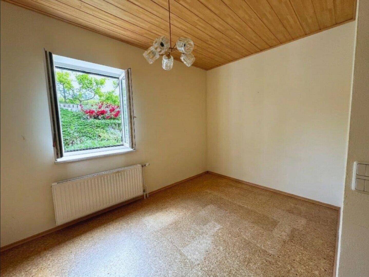 Helles Zimmer mit Korkboden, Holzdecke und Blick ins Grüne.