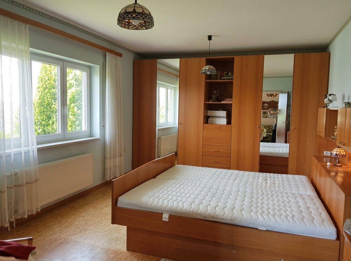 Gemütliches Schlafzimmer mit Holzmöbeln, Einbauschrank und Blick ins Grüne.