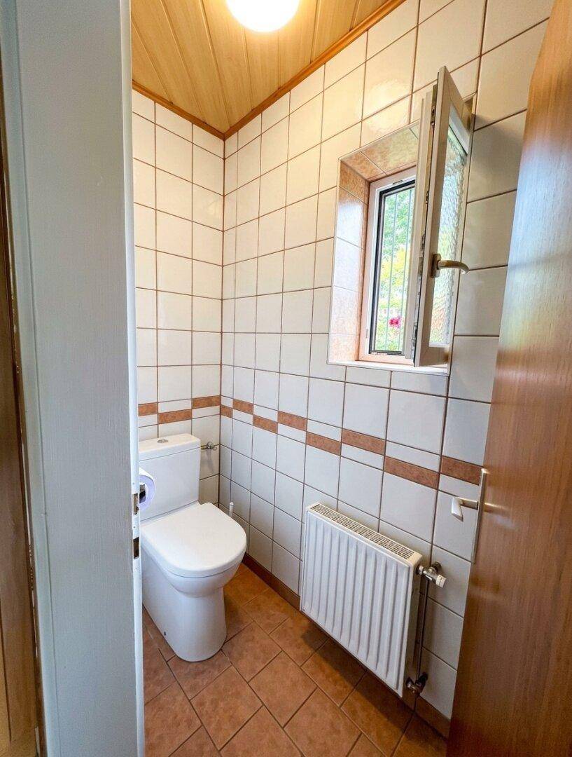 Kleines Gäste-WC mit Fliesen, Fenster und Holzdecke.