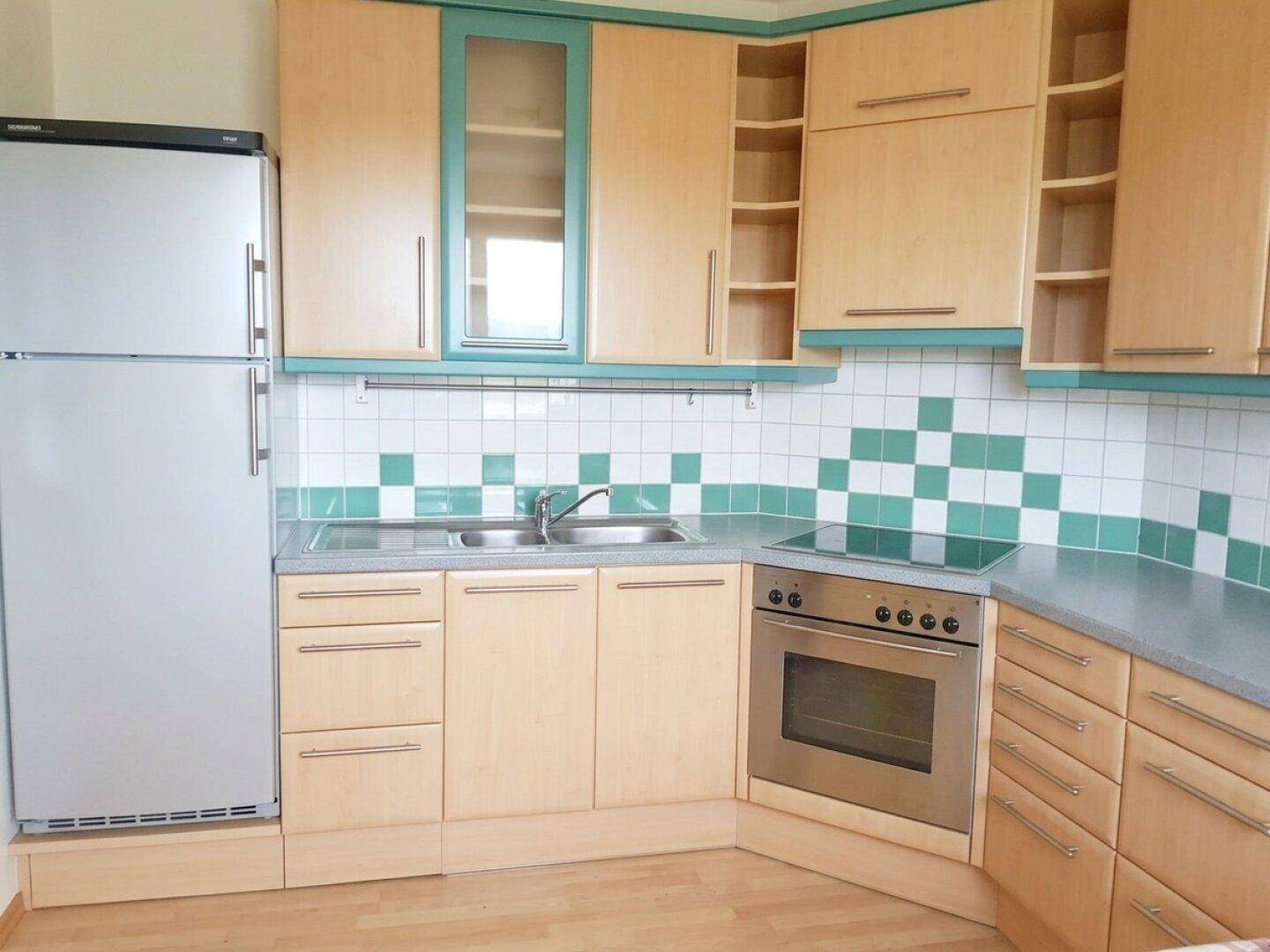 Funktionale Küche mit hellen Holzschränken, Einbaugeräten und Fliesenrückwand.